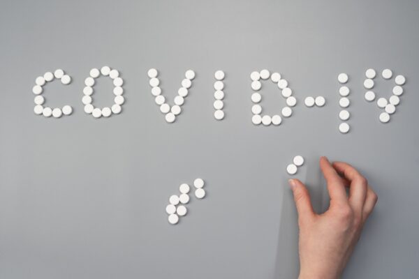 dozens of round vitamins spelling out the word covid-19