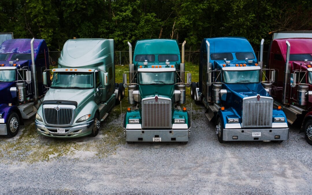 A line of different colored semi-trucks parked.